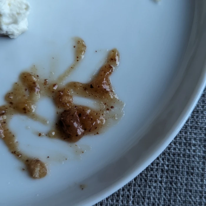 Close up of some of the almond paste, smeared onto the plate. Bits of crushed cardamom are visble in the dark brown paste.